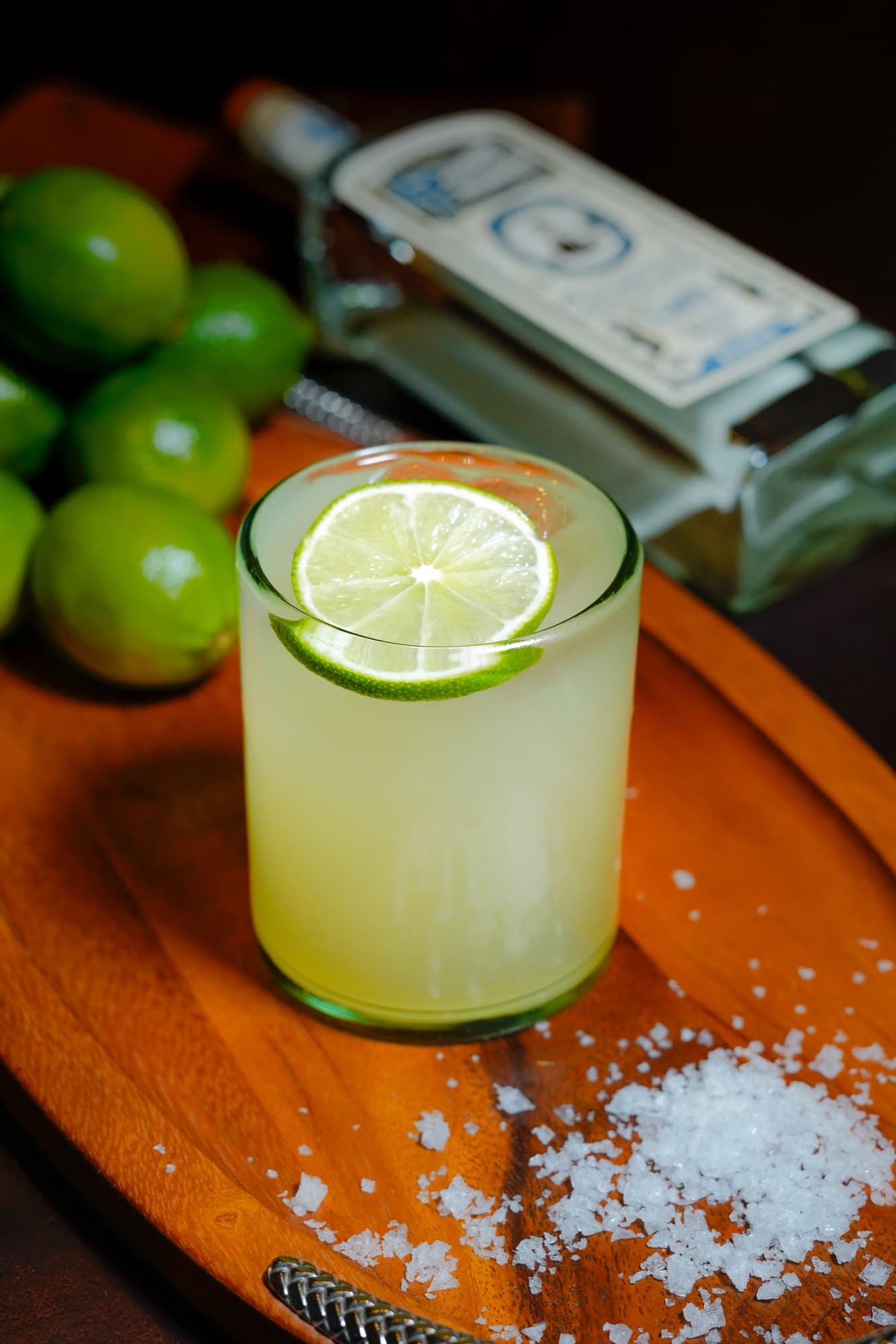 The Margarita Furtivo in a rocks glass with a lime wheel, on a wooden tray with limes, coarse salt and a bottle of Pedro Furtivo Blanco