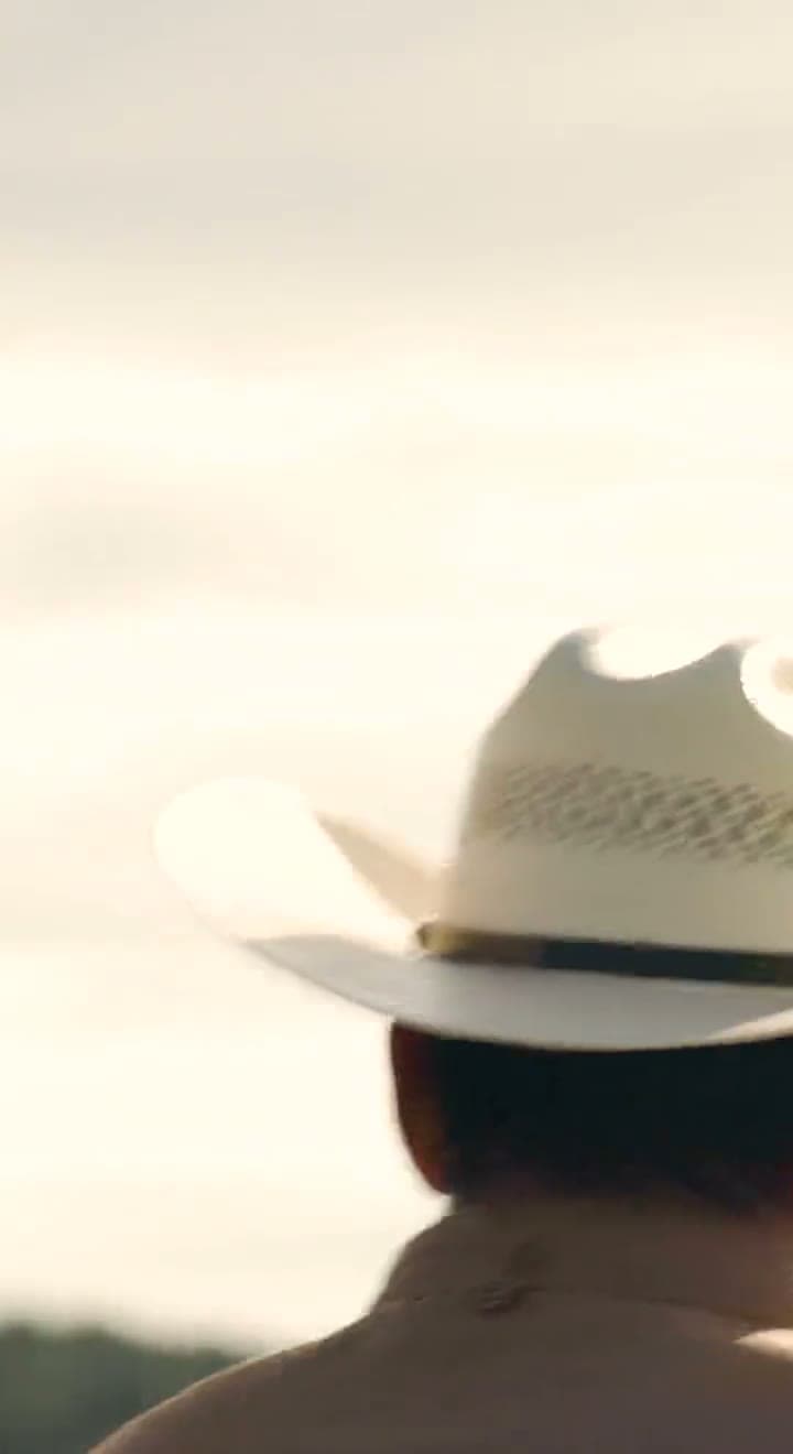Boots on a muddy estate lane, agave leaves and a straw hat against the sky