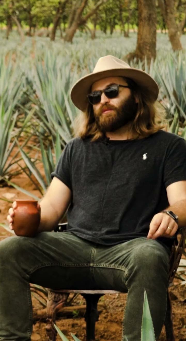 A meal laid out at the estate and a man in a hat seated with a clay cup