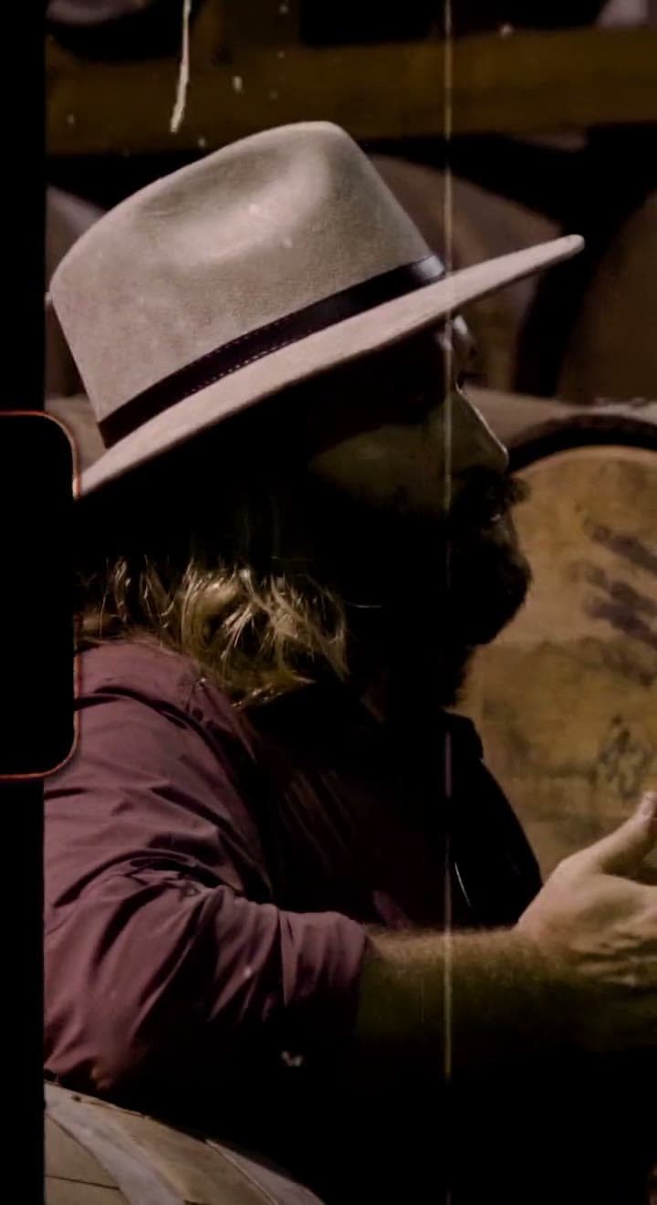 A man in a hat among the barrels in the barrel room