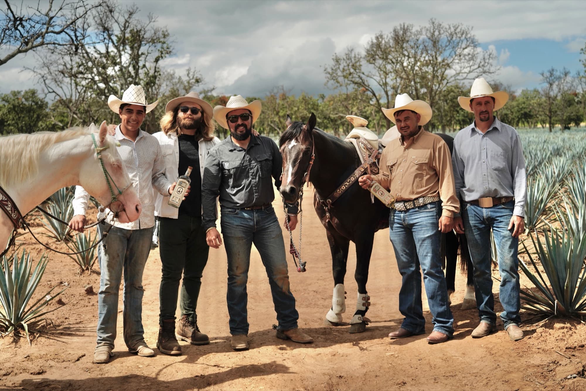 The estate crew standing with their horses among the agave