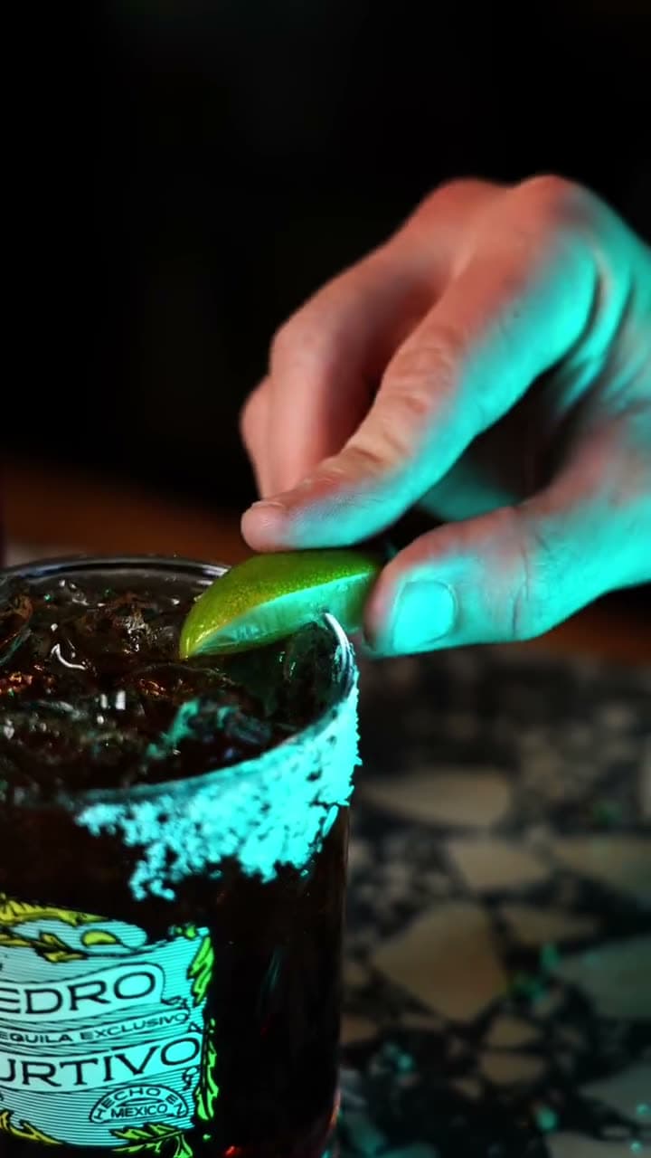 A lime going into a Batanga in a Pedro Furtivo rocks glass on a terrazzo bar
