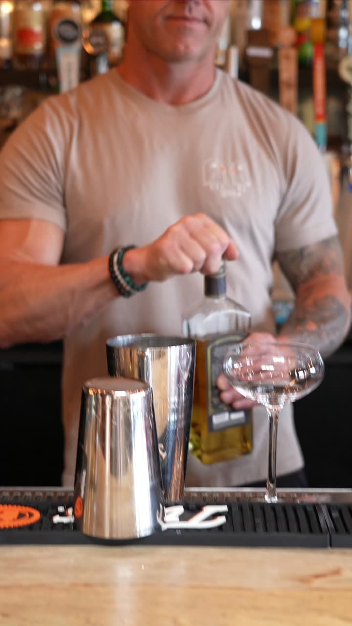 The bartender at Two Birds Taphouse building a cocktail over the bar mat